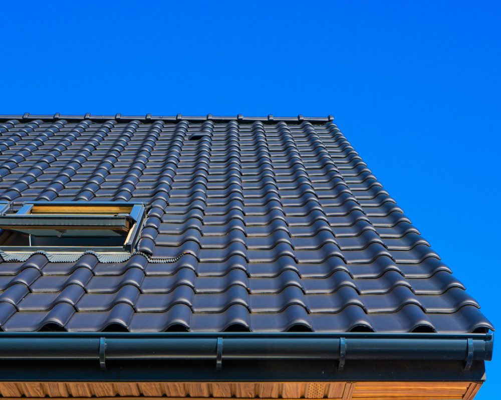 A vertical low angle closeup shot of the black roof of a building with a blue background